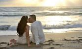 Sonnenaufgang und Hochzeitspaar am Strand von Florida kuessend