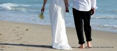 Hochzeitspaar geht am Strand spazieren Hand in Hand