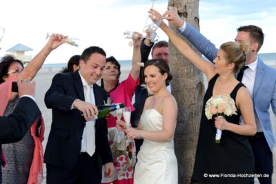 Froehliche Hochzeitsgesellschaft laesst Rosenblaetter auf Brautpaar regnen in Florida