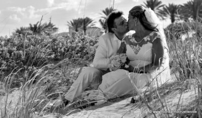 Heiraten in Florida mit Florida Hochzeiten Paar sitzt in den Duenen und kuesst sich
