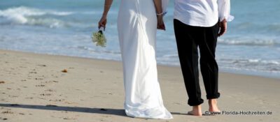 Hochzeitspaar geht am Strand spazieren Hand in Hand