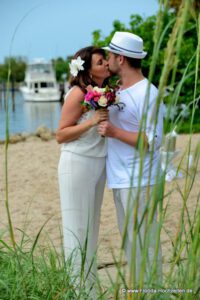 Hochzeitspaar am Strand mit Schilf und Meer im Hintergrund