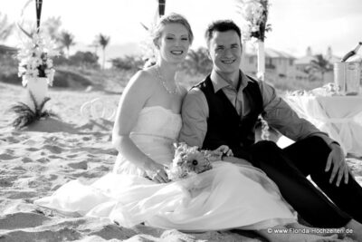 Hochzeitspaar am Strand sitzend mit Dekoration im Hintergrund