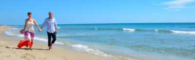 Paar laeuft am langgestreckten Sandstrand von Delray Beach entlang am blauen Meer