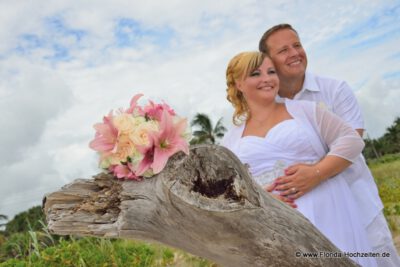 Hochzeitspaar mit dekorativem Baumstamm und wunderschoenem Brautstrauss