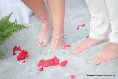 Florida Hochzeiten und Rosenblaetter im Sand mit Fuessen des Hochzeitspaares