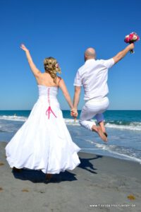 springendes Hochzeitspaar am Strand