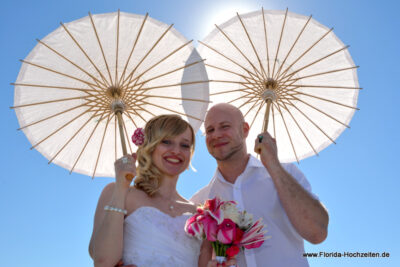 Hochzeitspaar mit Sonnenschirmen in weiss