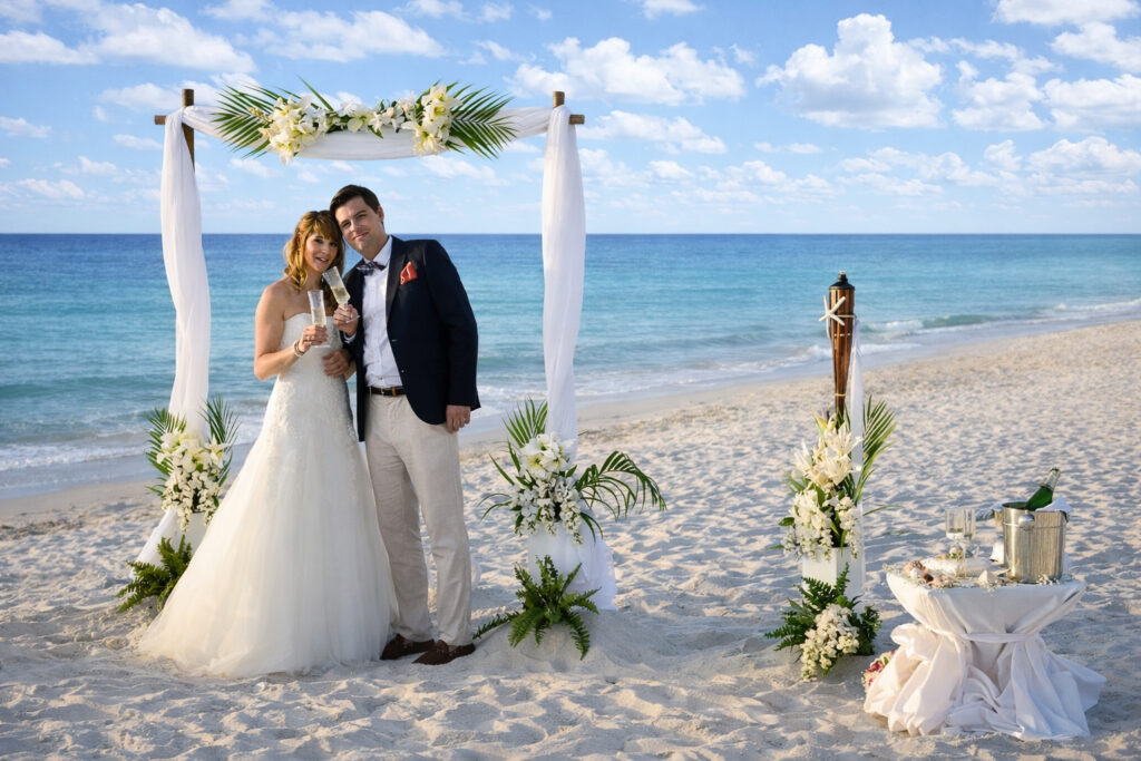 Brautpaar am Strand mit Sekt unter dem Lanaibogen